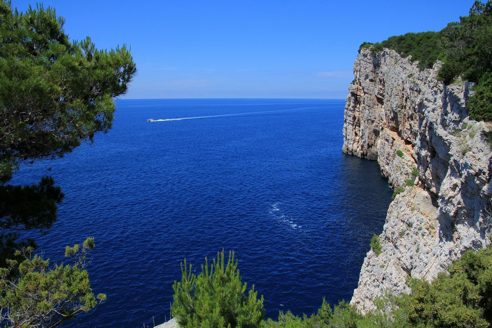 Un paysage côtier avec une falaise rocheuse et une mer bleue et limpide.
