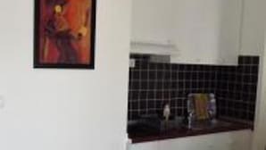 A kitchen with white cabinets, a black tiled backsplash, and a framed painting on the wall. - Cozy Apartment 16 With Double bed Sleeper Couch (Split)