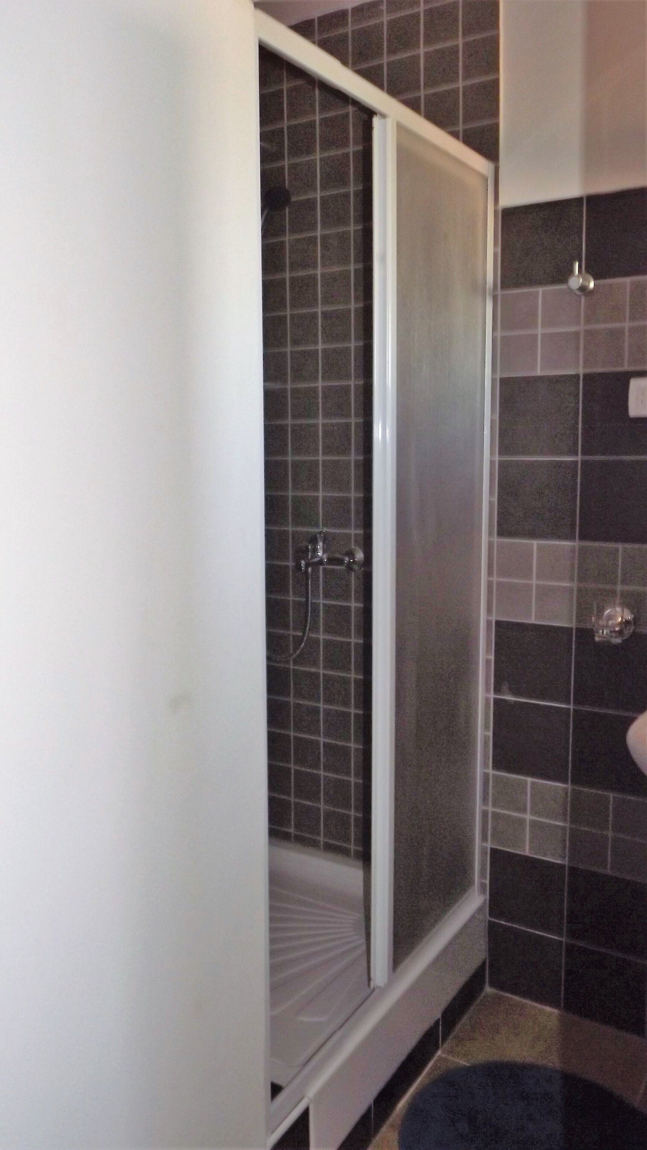 A bathroom with a shower enclosure, tiled walls, and a white sink.