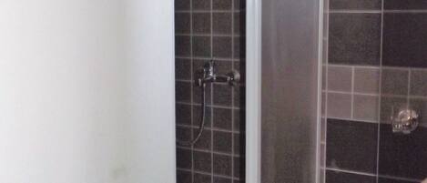 A bathroom with a shower enclosure, tiled walls, and a white sink.