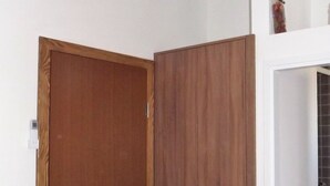A room with a wooden wardrobe, a white door, and an air conditioning unit on the wall. - Cozy Apartment 16 With Double bed Sleeper Couch (Split)
