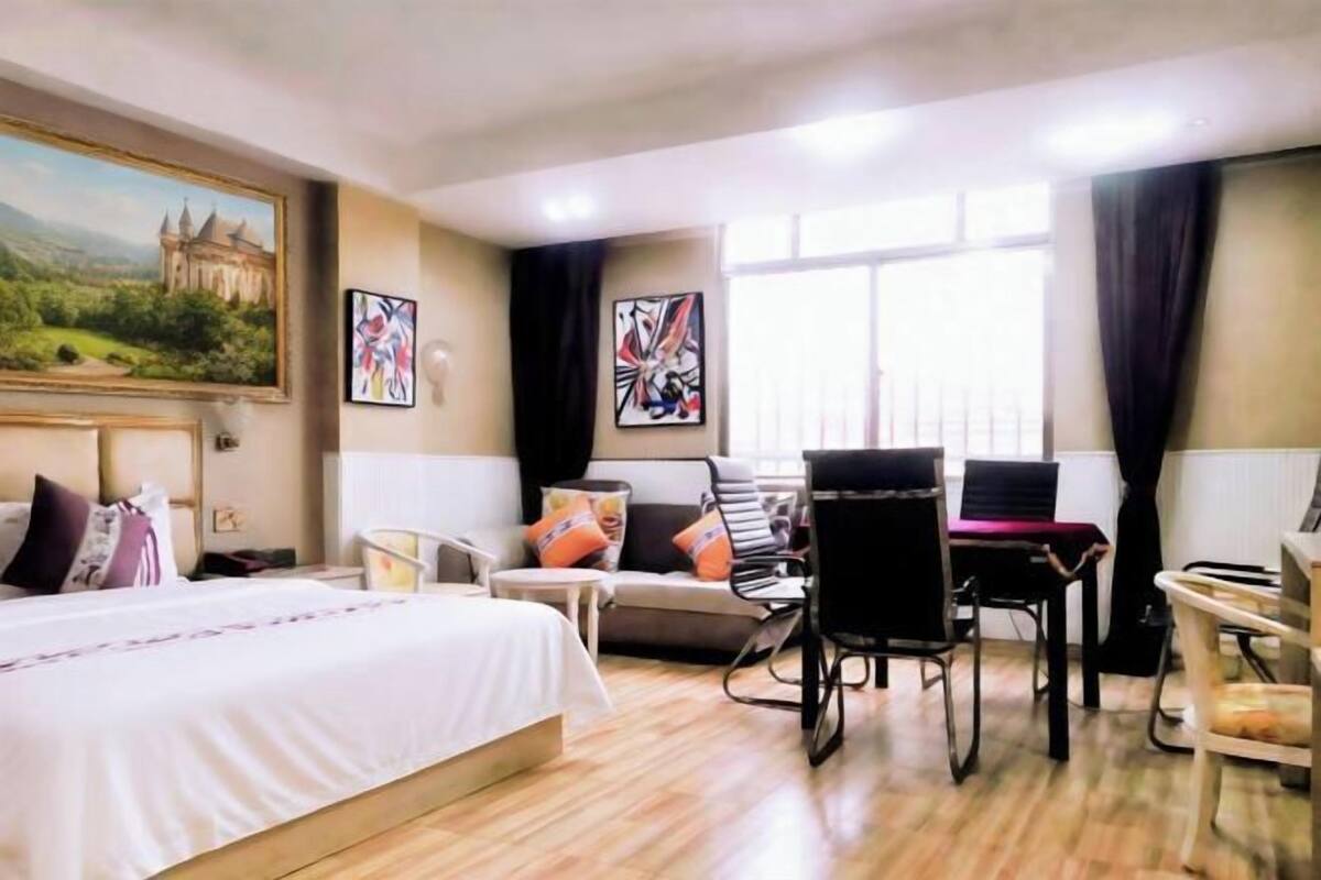 A hotel room with a bed, a desk, a chair, and a window with curtains.