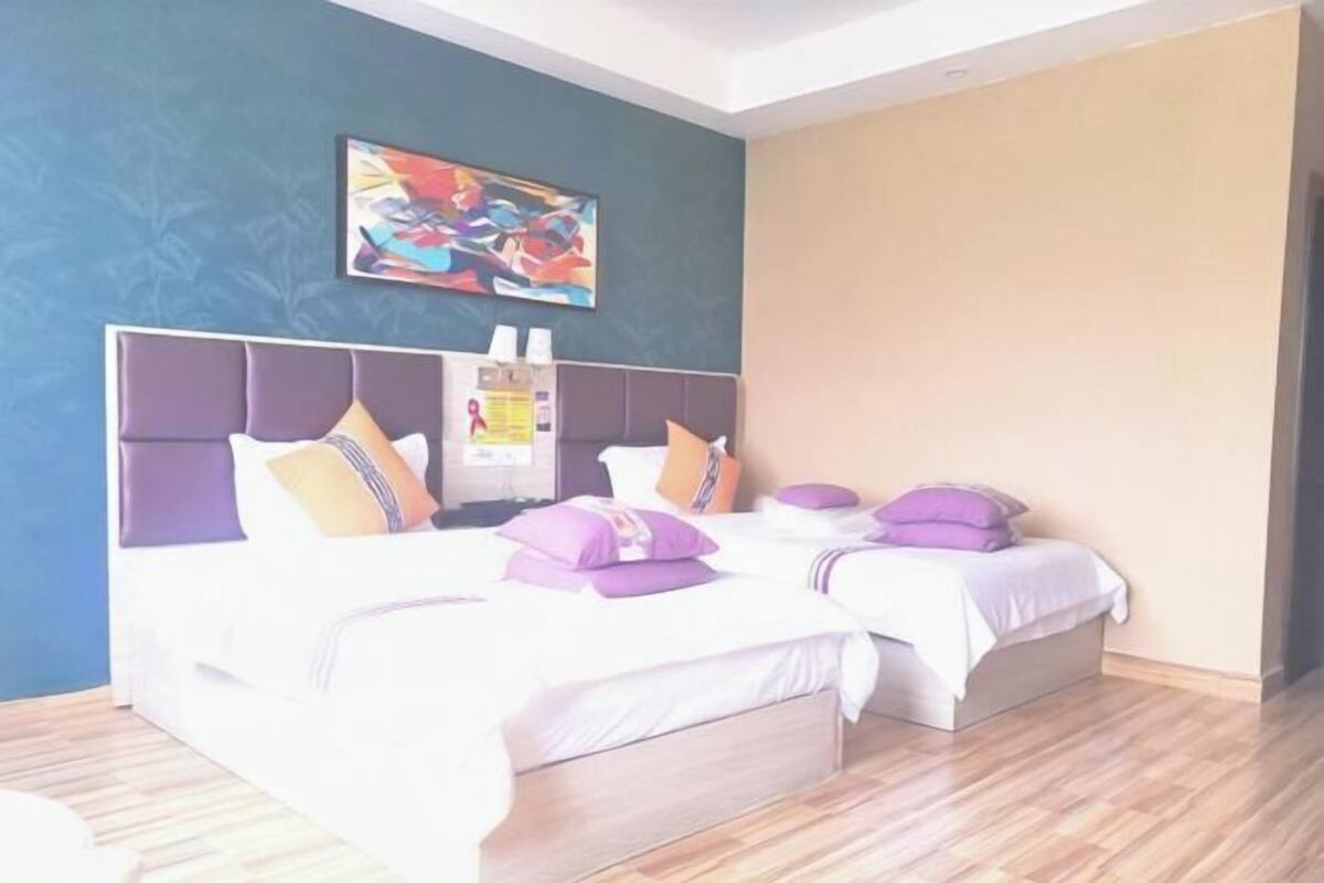 A hotel room with two beds, a large headboard, and a colorful abstract painting on the wall.