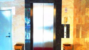 Un ascensor con detalles metálicos, puerta de vidrio y pared de mármol.