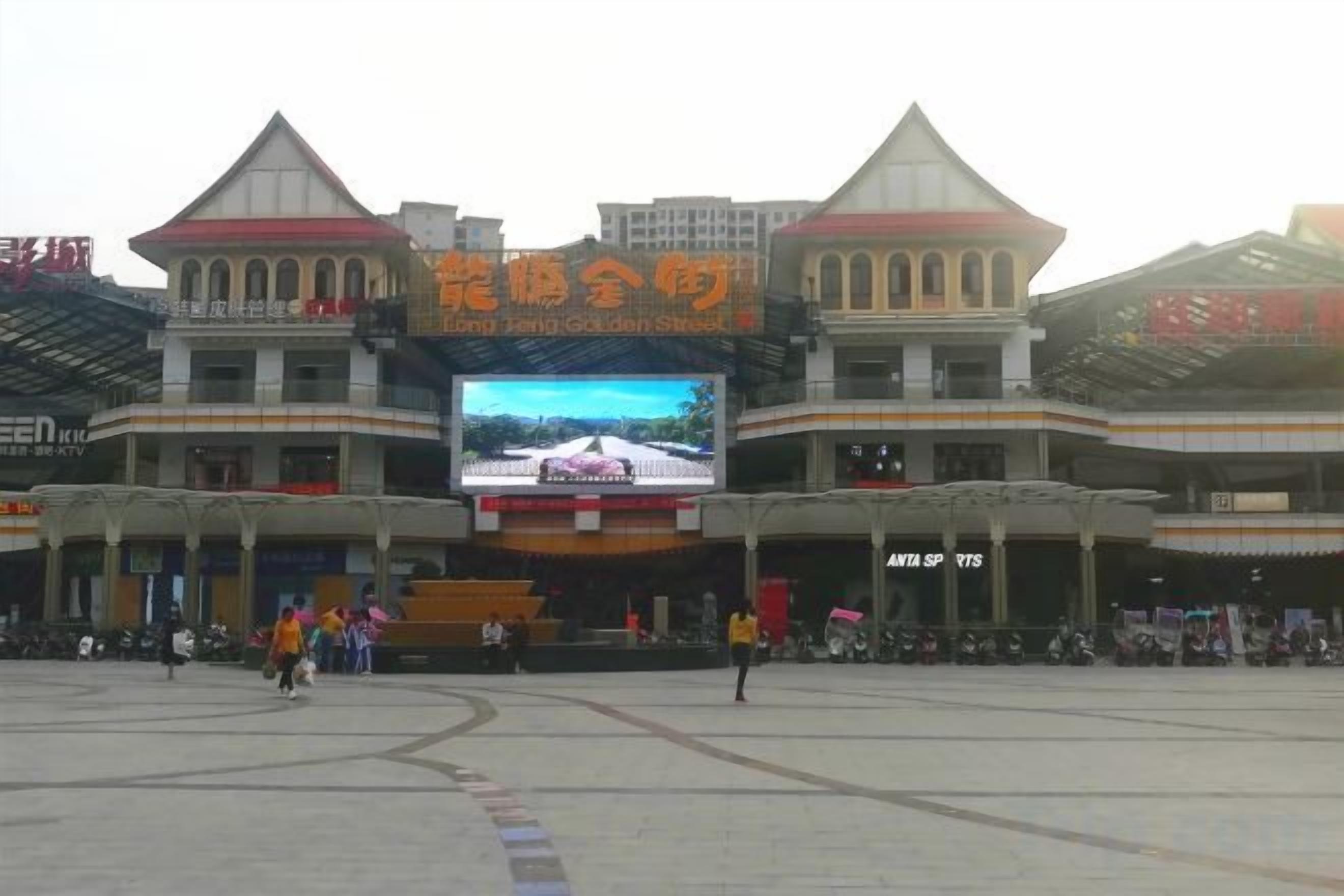 A building with a large digital screen displaying a scenic view, multiple levels with balconies, and a central open area.
