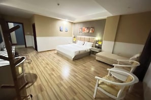 A hotel room with a bed, a desk, a chair, and a sofa.