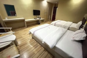 A hotel room with two beds, a desk, a TV, and a small seating area.