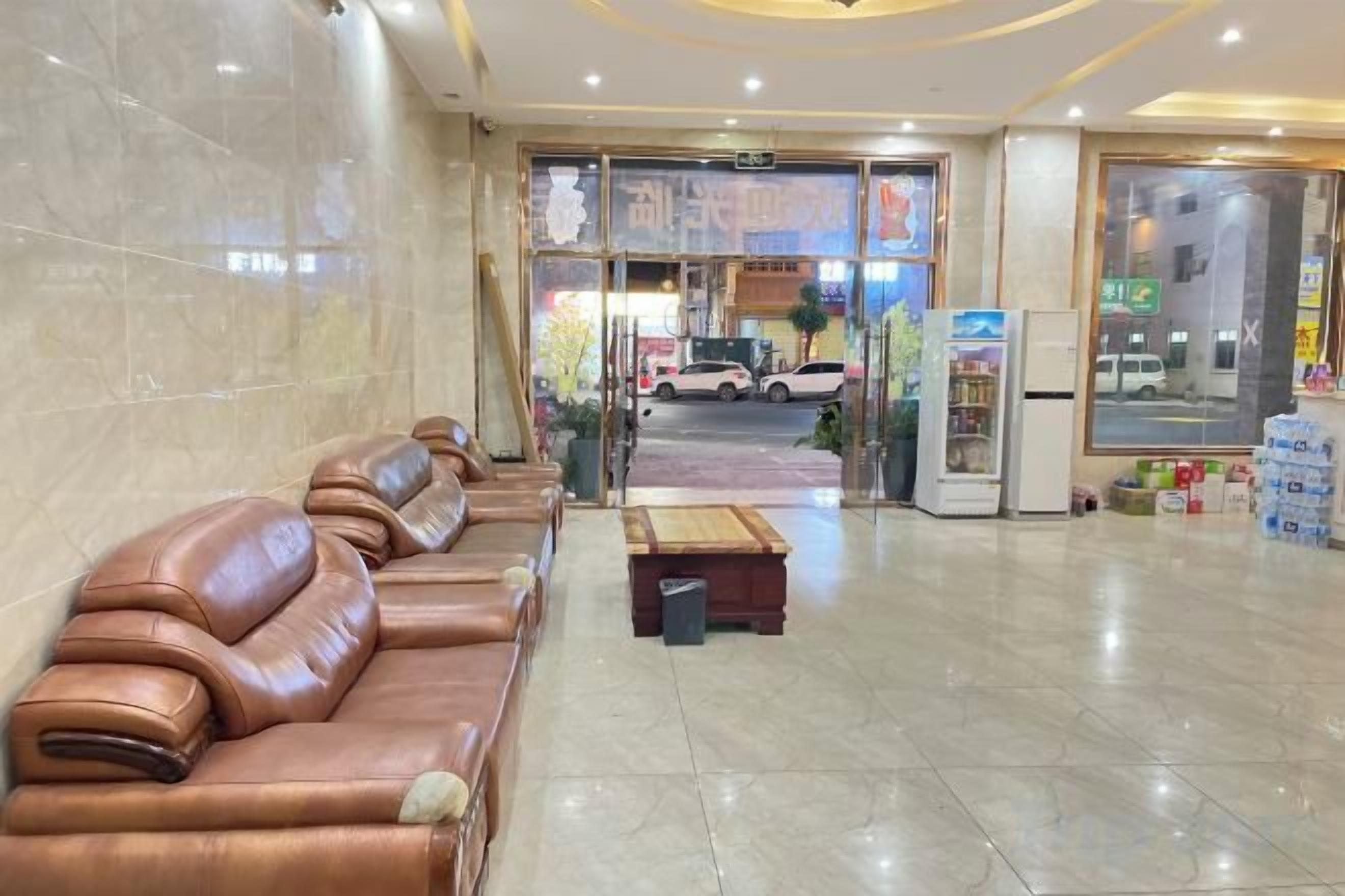 A hotel lobby with leather sofas, a reception desk, and a view of the street outside.