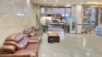 A hotel lobby with leather sofas, a reception desk, and a view of the street outside.