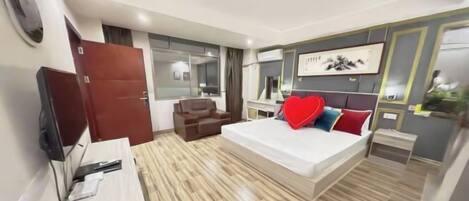 Habitación de hotel moderna con una cama grande, un escritorio, un televisor y un armario.