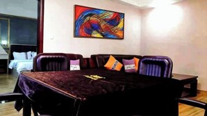 Un salón de conferencias con una mesa oscura, cuatro sillas y un cuadro abstracto colorido en la pared.