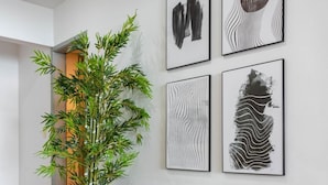 A hallway with a wooden floor, a potted plant, a glass table, and four framed artworks on the wall. - View of Copacabana Beach A1103 (Rio de Janeiro)