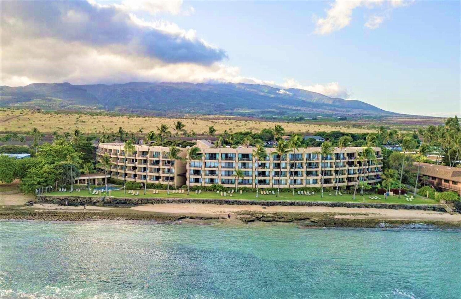A hotel with multiple floors, a pool, and a view of a mountain and beach.