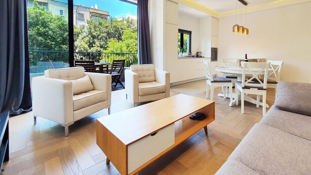 A modern living room with a sofa, two armchairs, a coffee table, and a dining area with a table and chairs. - Dizengoff Brique in Tel Aviv-yafo (Tel Aviv)