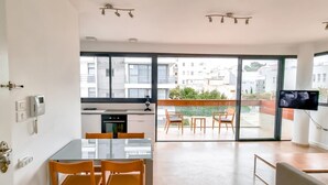 A modern apartment with a kitchen, dining area, and balcony with a TV. - Kalisher Ophrys in Tel Aviv-yafo (Tel Aviv)