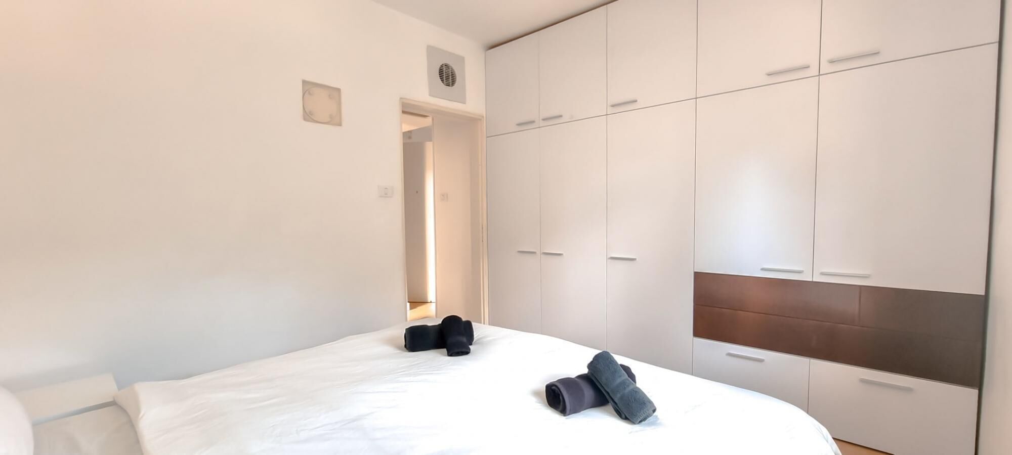 Una habitación de hotel con cama, armario y puerta que da a otra estancia.