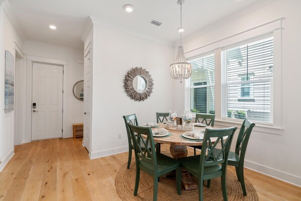 A dining area with a round table, green chairs, a chandelier, and a large mirror on the wall. - It's A Great Day on 30a Beach Vacation home (Inlet Beach)