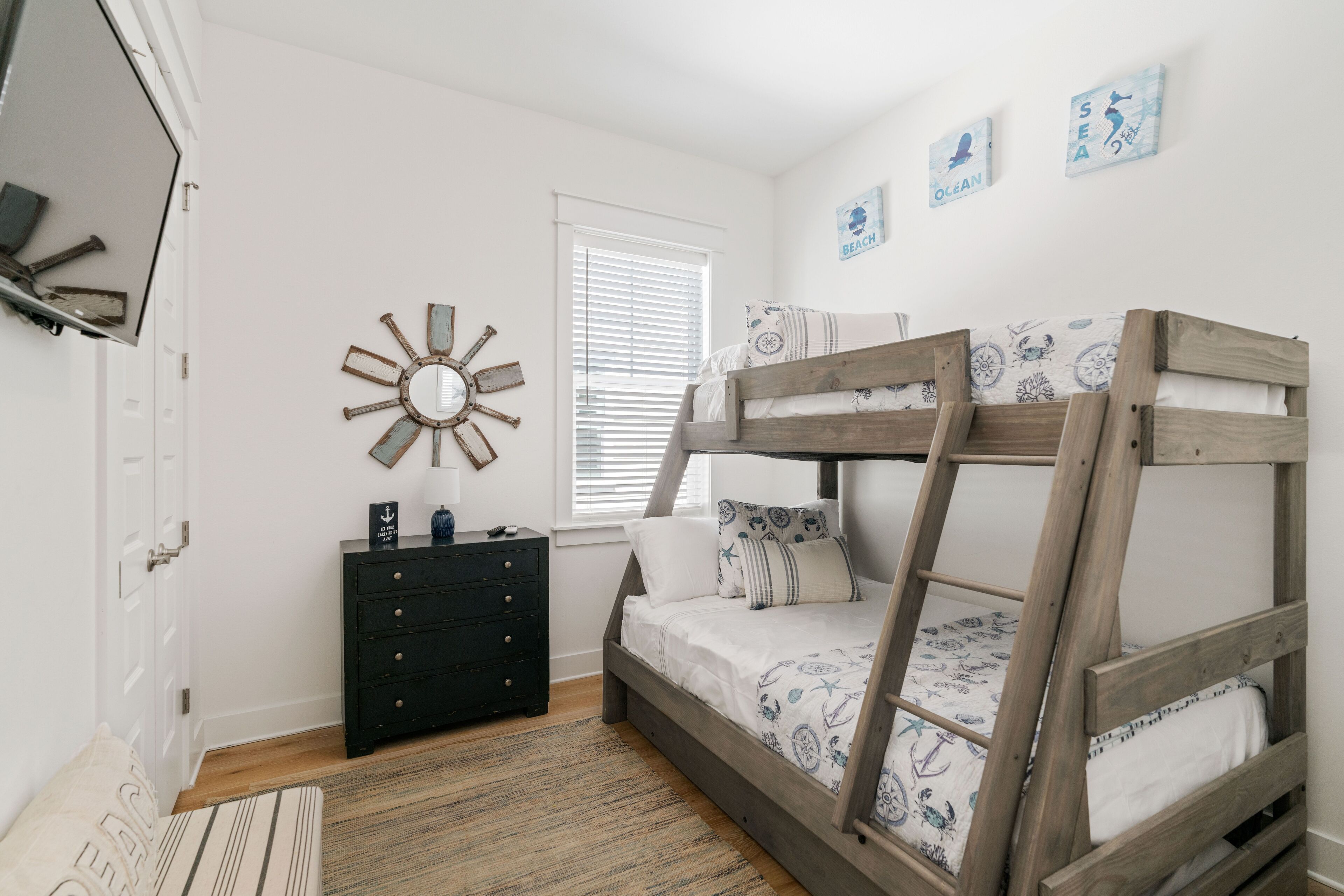 A bedroom with a bunk bed, a dresser, a mirror, and wall art.