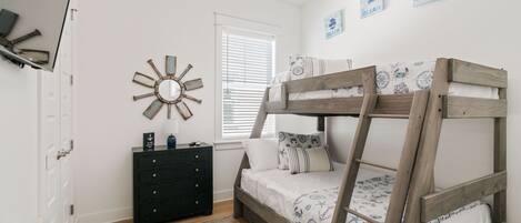 A bedroom with a bunk bed, a dresser, a mirror, and wall art.