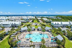 Un complexe hôtelier doté d’une piscine centrale, entourée d’espaces de détente, d’un parking et offrant une vue sur l’océan.