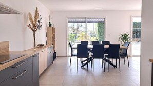 Una cuina moderna amb taulell de fusta, armaris integrats i zona de menjador amb taula i cadires.