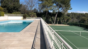 Una piscina junto a una cancha de tenis.