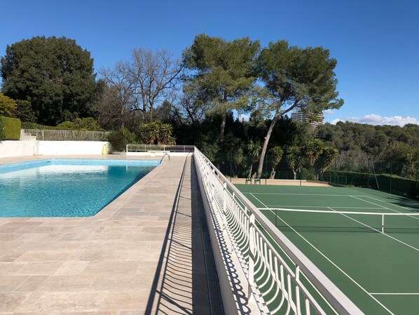 A swimming pool with a tennis court adjacent to it.
