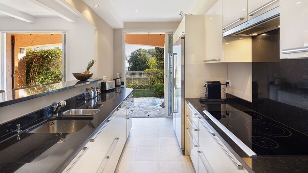 Una cocina moderna con una encimera larga, electrodomésticos de acero inoxidable y vistas a un jardín.
