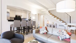 Una sala de estar moderna con un sofá gris, una mesa de centro y una zona de bar con taburetes altos.