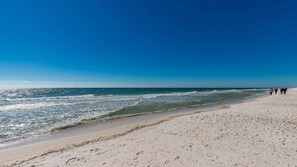 A beach with a clear sky, calm sea, and footprints on the sand. - Island Winds East by Brett/Robinson Vacations (Gulf Shores)