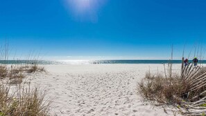 A beach with sand, sea, and clear sky.
