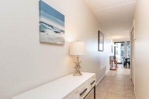 A hallway with a white console table, a starfish lamp, and a framed picture of a beach scene. - Island Winds East by Brett/Robinson Vacations (Gulf Shores)
