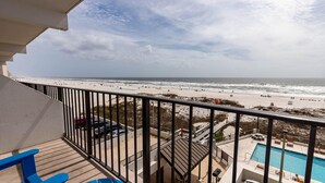 Un balcón con vista a una playa y una piscina.