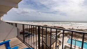 A balcony with a view of a beach and a swimming pool.