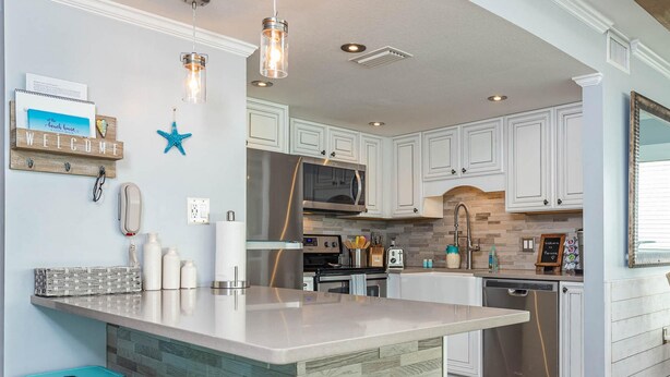 Una cocina moderna con armarios blancos, una isla grande y taburetes de bar color turquesa.