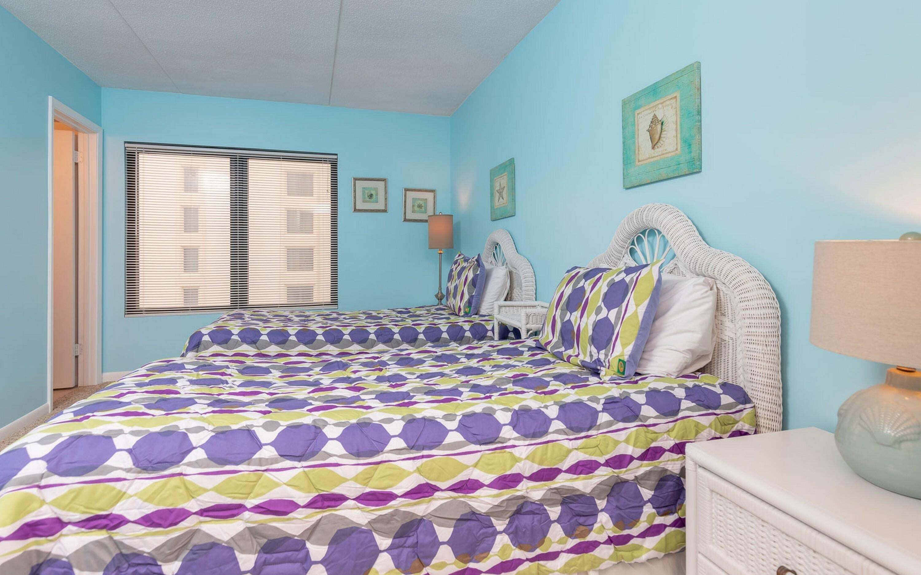 Een slaapkamer met een bed, een stoel, een nachtkastje, een lamp en een raam met jaloezieën.