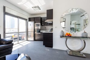 A modern kitchen with dark cabinetry, a glass dining table, and a large mirror.
