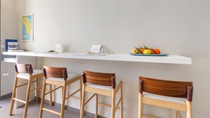 A kitchen with a white countertop, three wooden bar stools, and a fruit bowl with apples, oranges, and lemons. - 2674 B&B Albatro - Camera Tripla (Taviano)