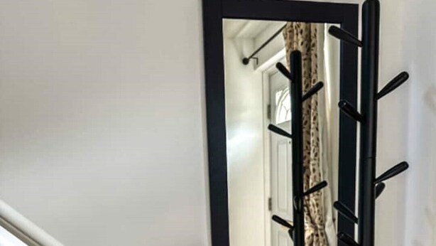 A staircase with a white handrail and a black coat rack with hooks. - Comfy house in West Lothian - 10 min from the airport! (Broxburn)