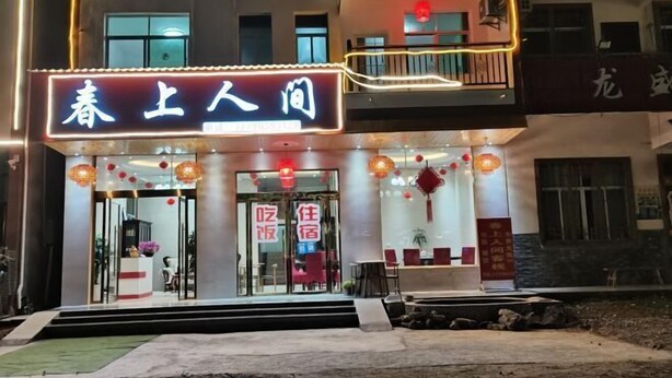 A hotel entrance with a neon sign, glass doors, and red lanterns.