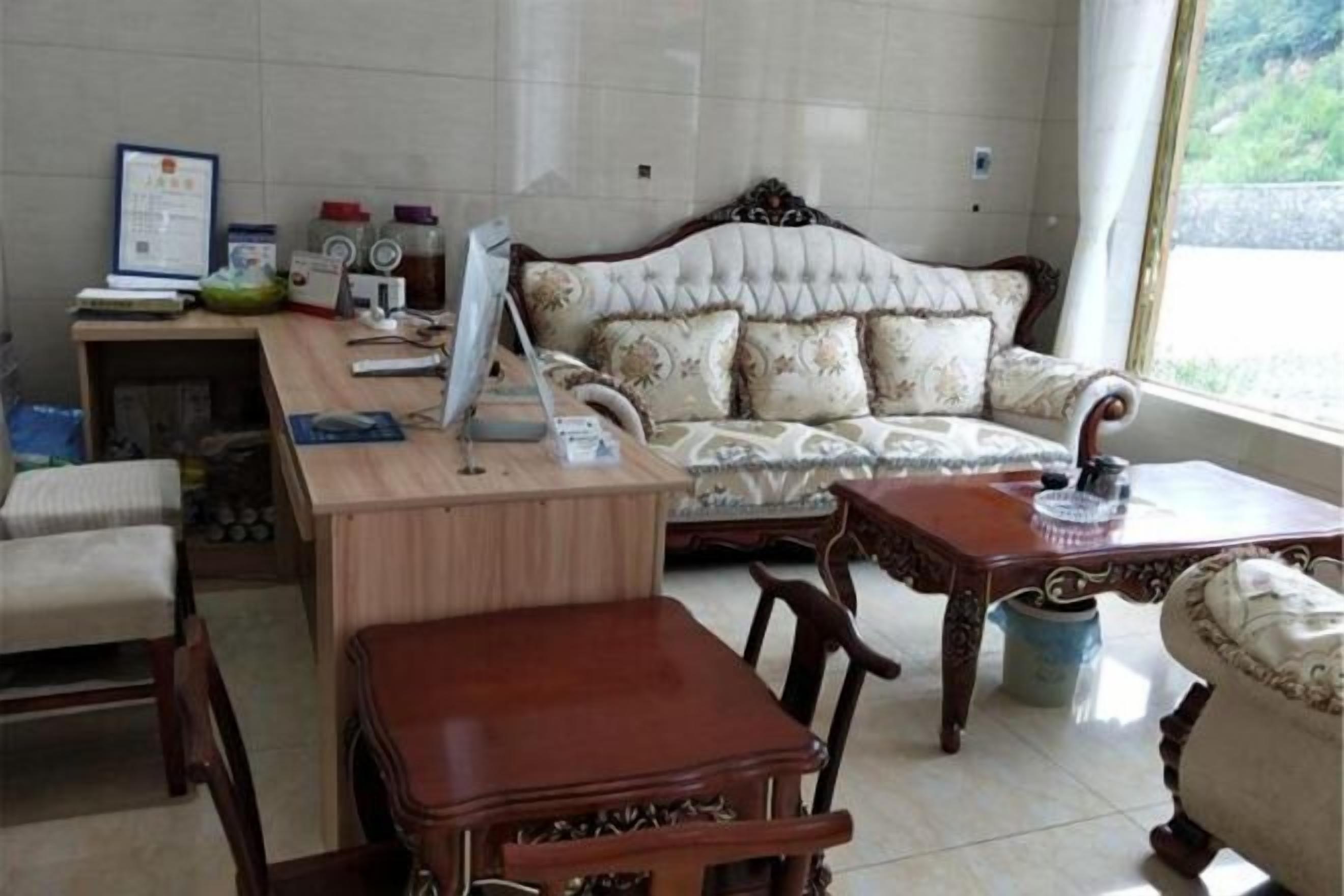 A room with a wooden desk, a sofa, and a dining table.