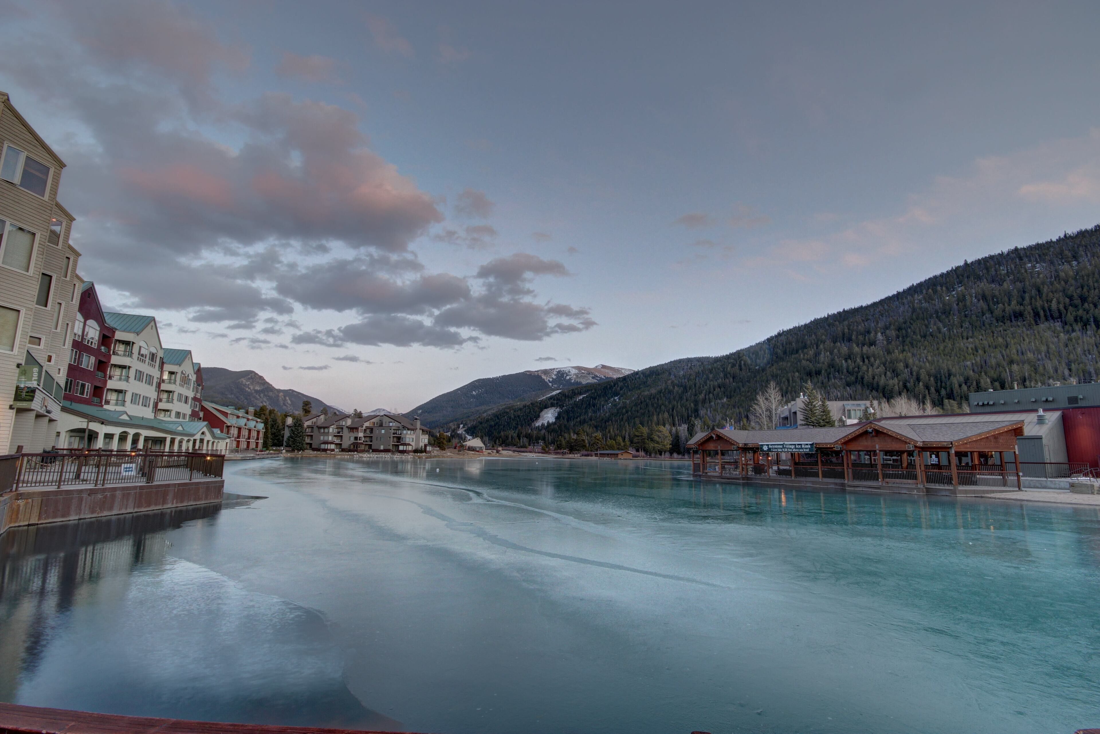A waterfront hotel with a view of mountains and a calm lake.