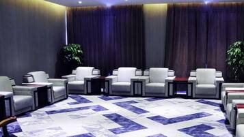 Un vestíbulo de hotel con una zona de estar, una alfombra grande y una planta.