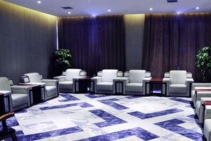 Un hall d’hôtel avec un espace salon, une grande moquette et une plante.