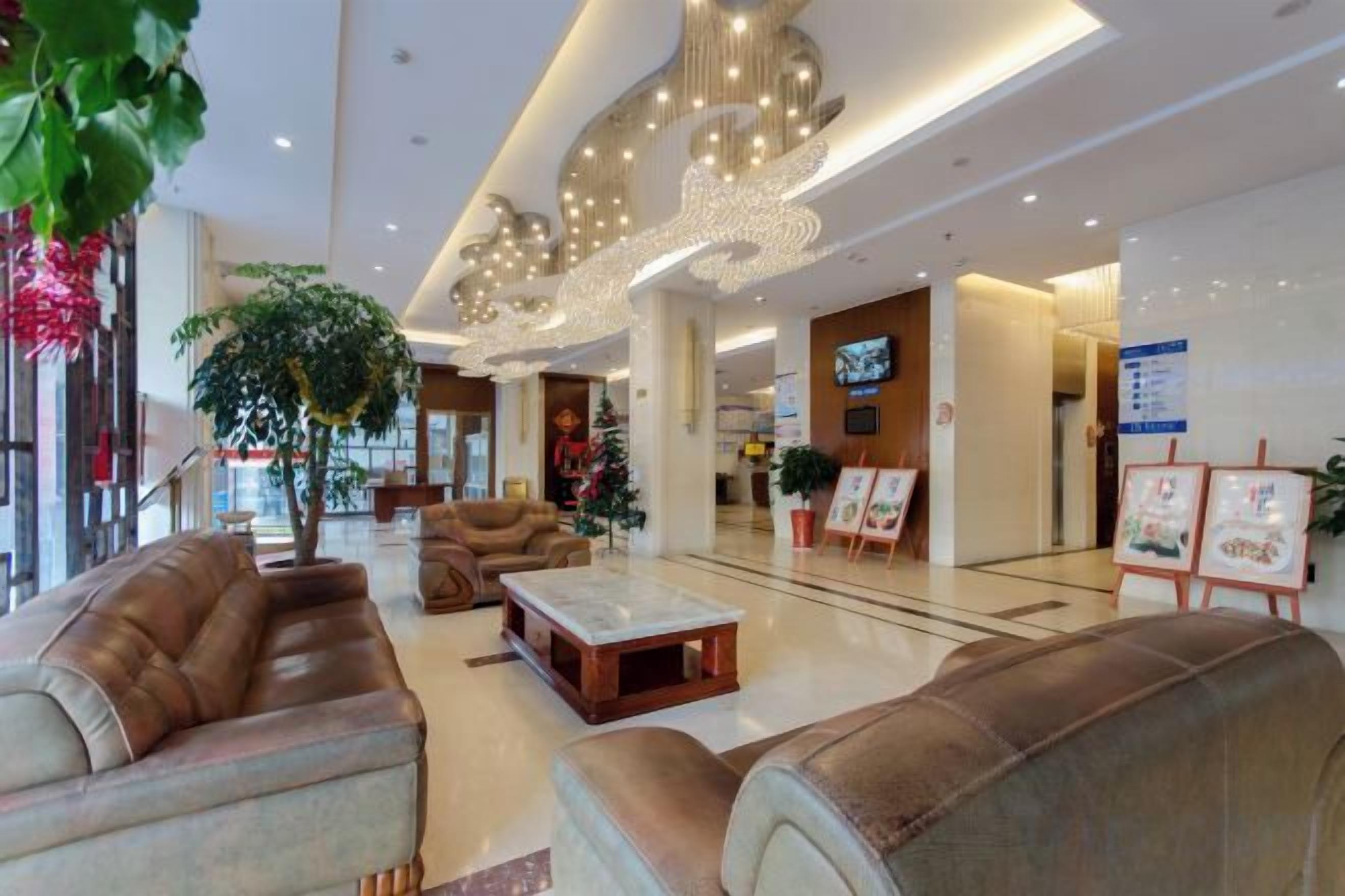 A spacious lobby with leather sofas, a coffee table, and a large plant.