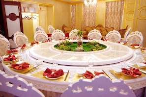 A round table with a central floral arrangement, surrounded by ornate chairs, in a well-lit room with a chandelier. - Dongsheng Hotel (Yunxi)