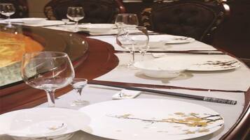 Una mesa de comedor dispuesta con platos, vasos y cubiertos, indicando una preparación para la comida.