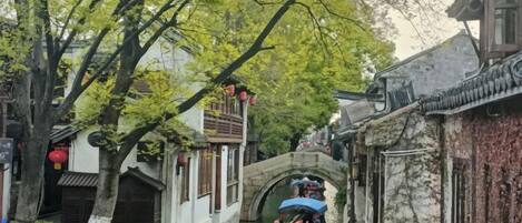 A narrow waterway with traditional buildings on either side, a stone bridge, and boats.