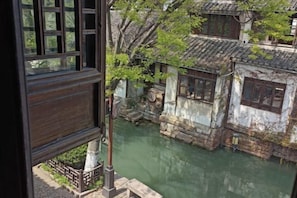 A traditional Chinese courtyard with stone buildings, a wooden railing, and a water feature.