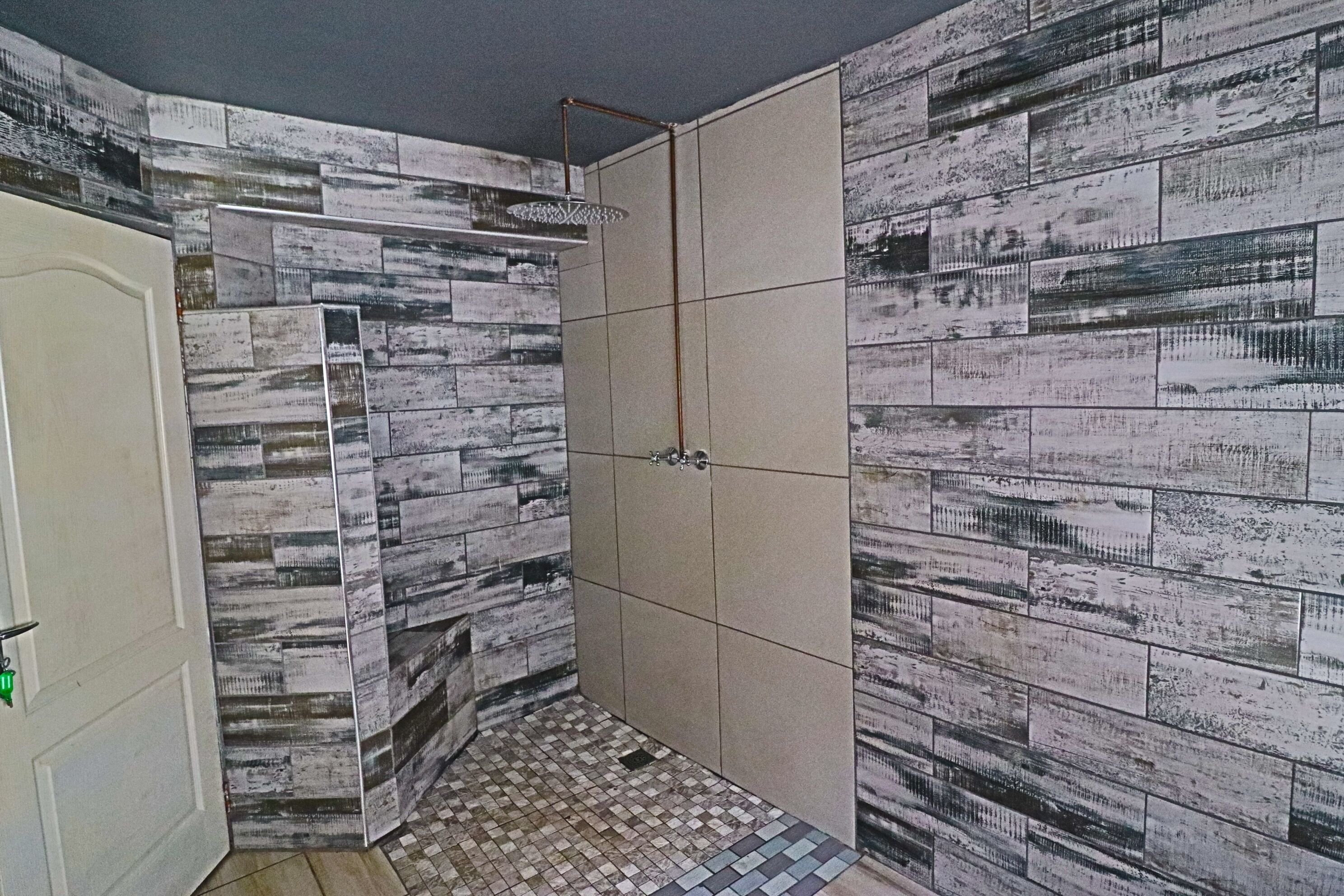 A bathroom with a shower, tiled walls, and a tiled floor.